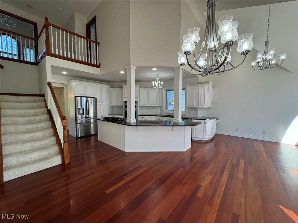 Kitchen with dark countertops, a high ceiling, dark wood-style floors, a chandelier, and stainless steel appliances