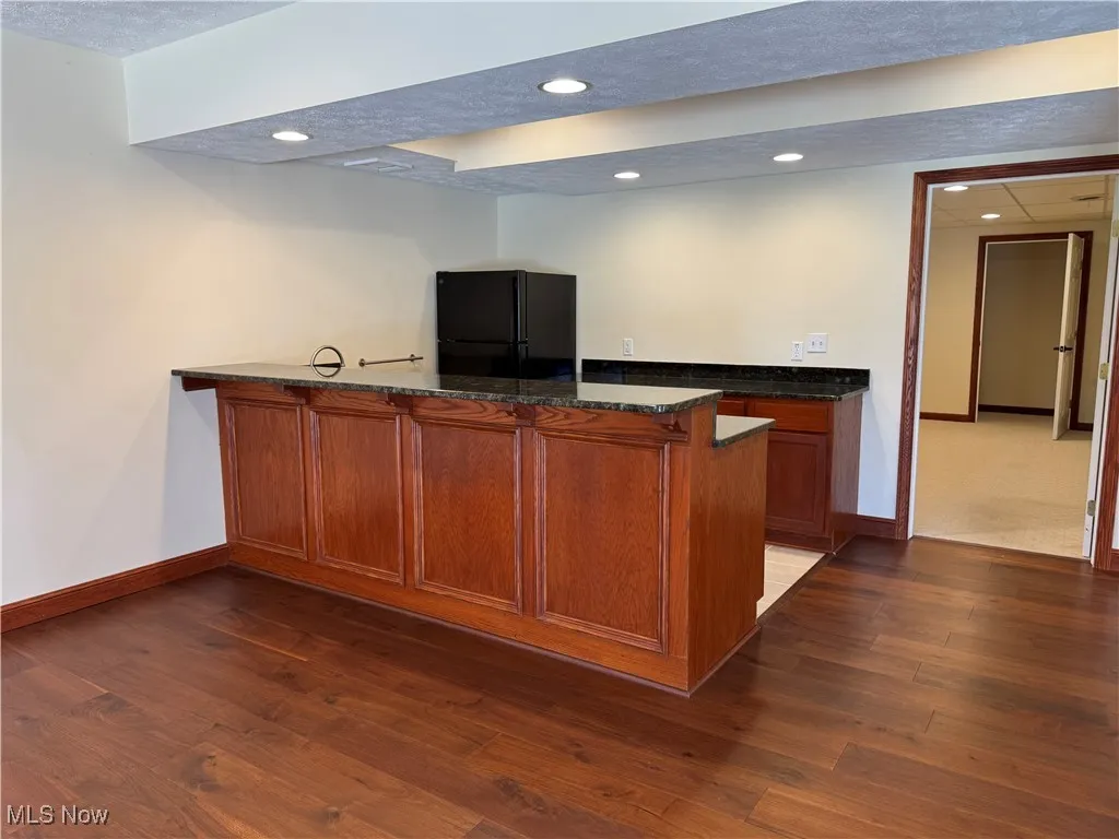 Bar featuring baseboards, freestanding refrigerator, dark wood-style flooring, and recessed lighting