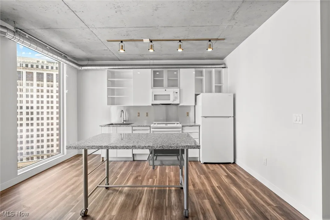 Kitchen featuring sink, dark hardwood / wood-style flooring, white appliances, and white cabinetry