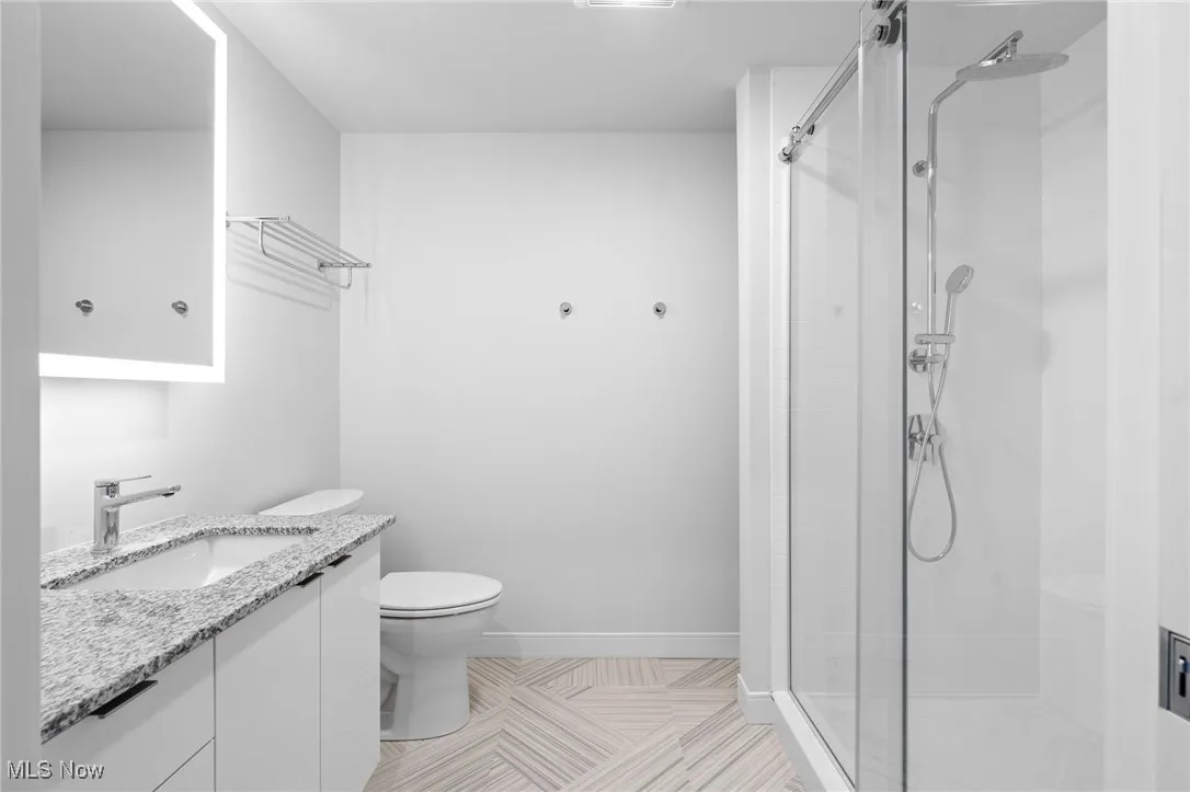 Bathroom featuring walk in shower, vanity, and toilet