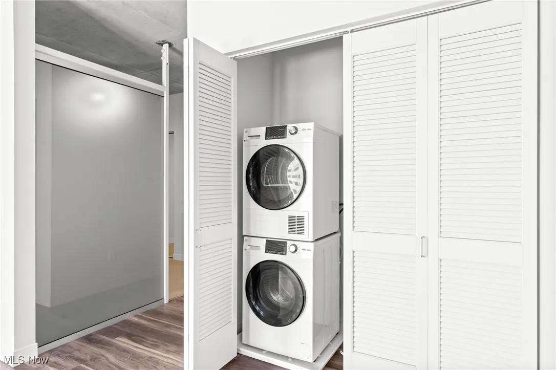 Washroom featuring dark hardwood / wood-style floors and stacked washer / drying machine