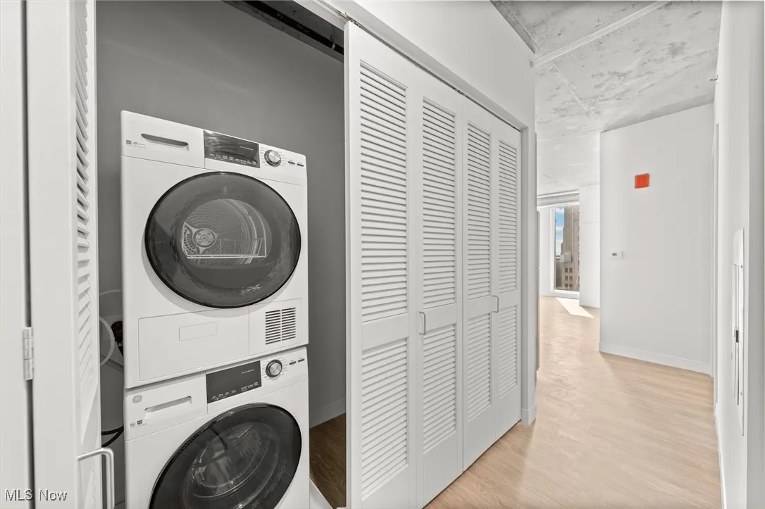 Laundry room featuring stacked washer / dryer, a barn door, and light wood-type flooring