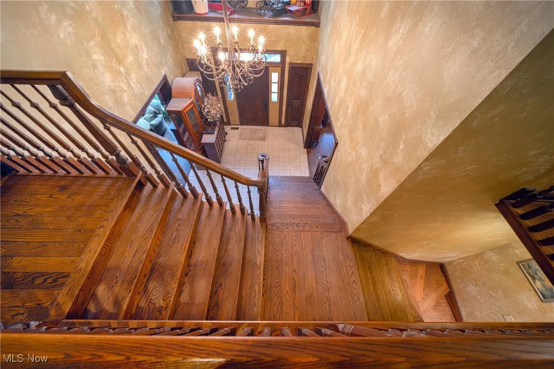 Stairs featuring dark wood-type flooring and an inviting chandelier