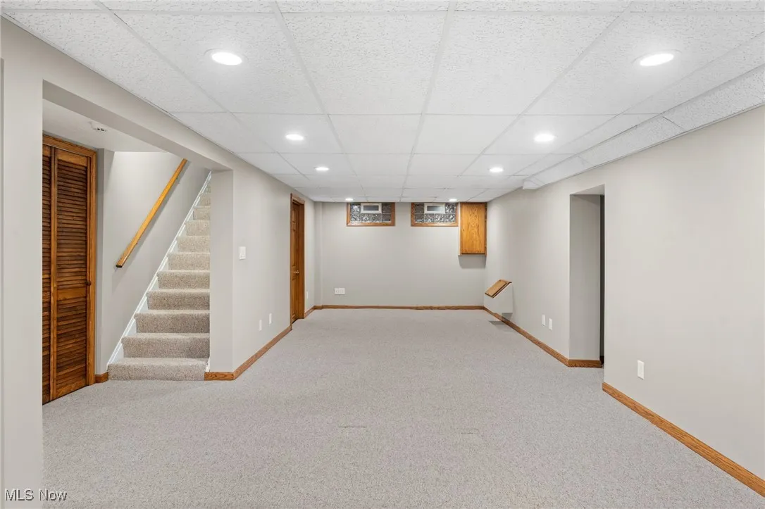 Basement featuring a drop ceiling and light colored carpet