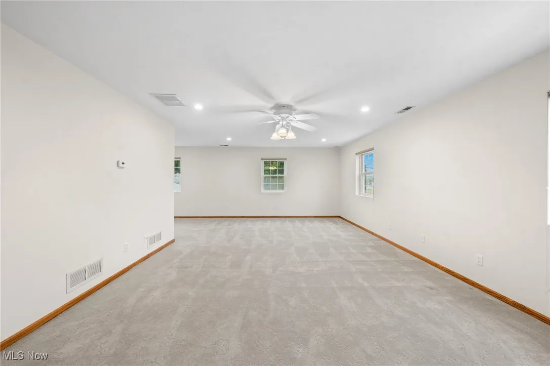 Empty room with ceiling fan and light colored carpet