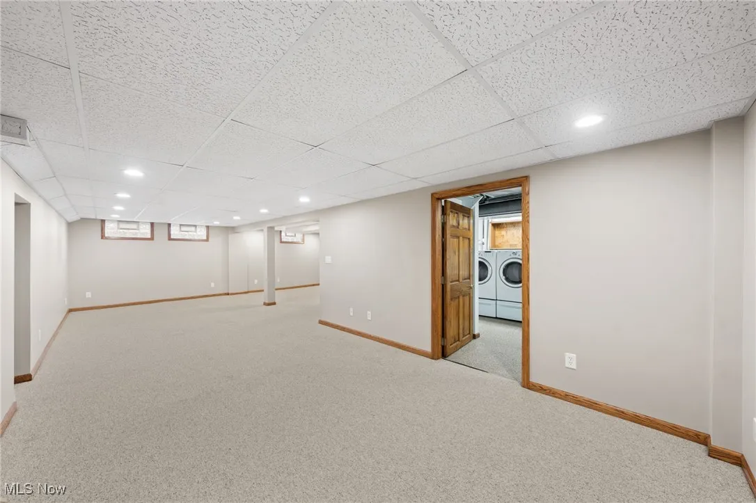 Basement featuring washer and clothes dryer, light carpet, and a paneled ceiling