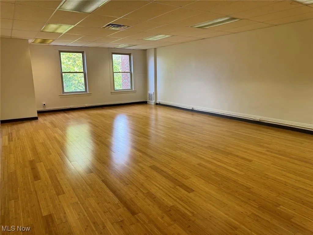 Empty room with a paneled ceiling and light hardwood / wood-style floors