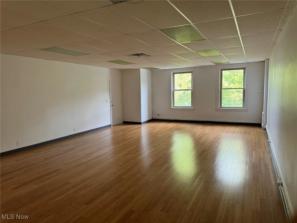 Empty room with a paneled ceiling and light hardwood / wood-style flooring