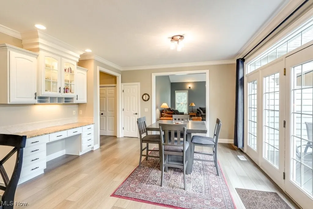 Dining room with ornamental molding, light wood-type flooring, and a healthy amount of sunlight