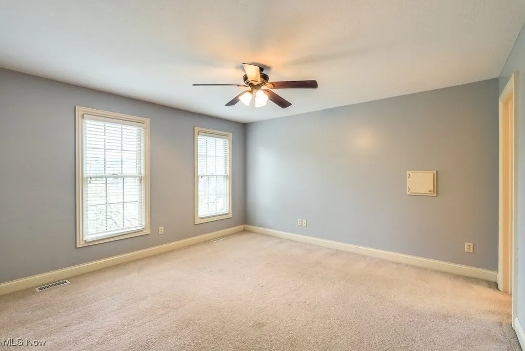 Spare room featuring light carpet and ceiling fan