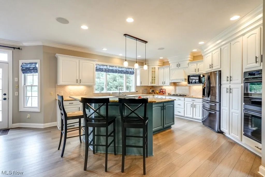 Kitchen with black appliances, a kitchen bar, a kitchen island, and white cabinets