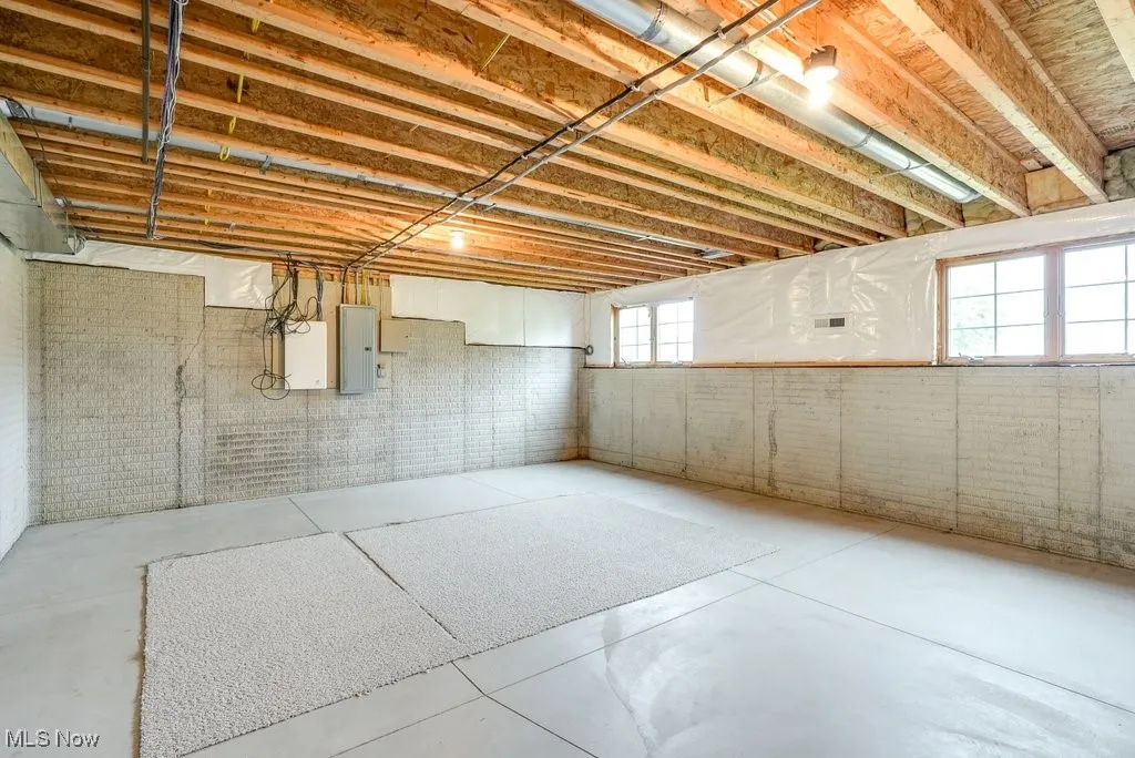 Basement with brick wall, electric panel, and plenty of natural light