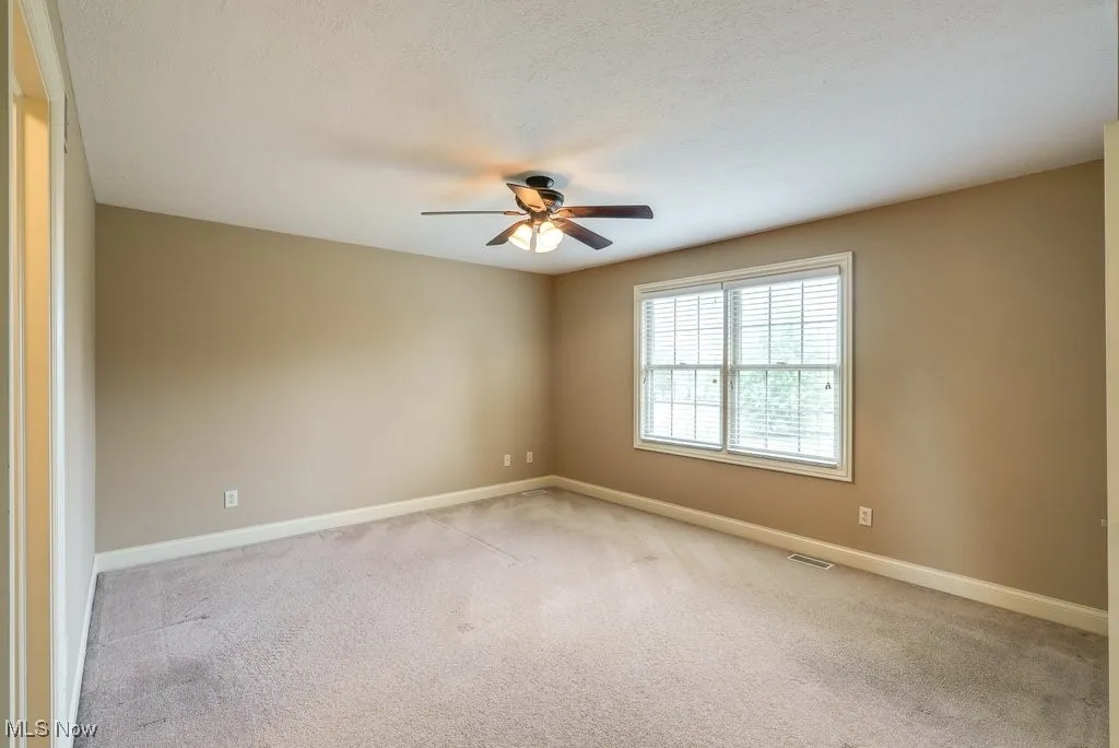 Carpeted spare room featuring ceiling fan and a textured ceiling