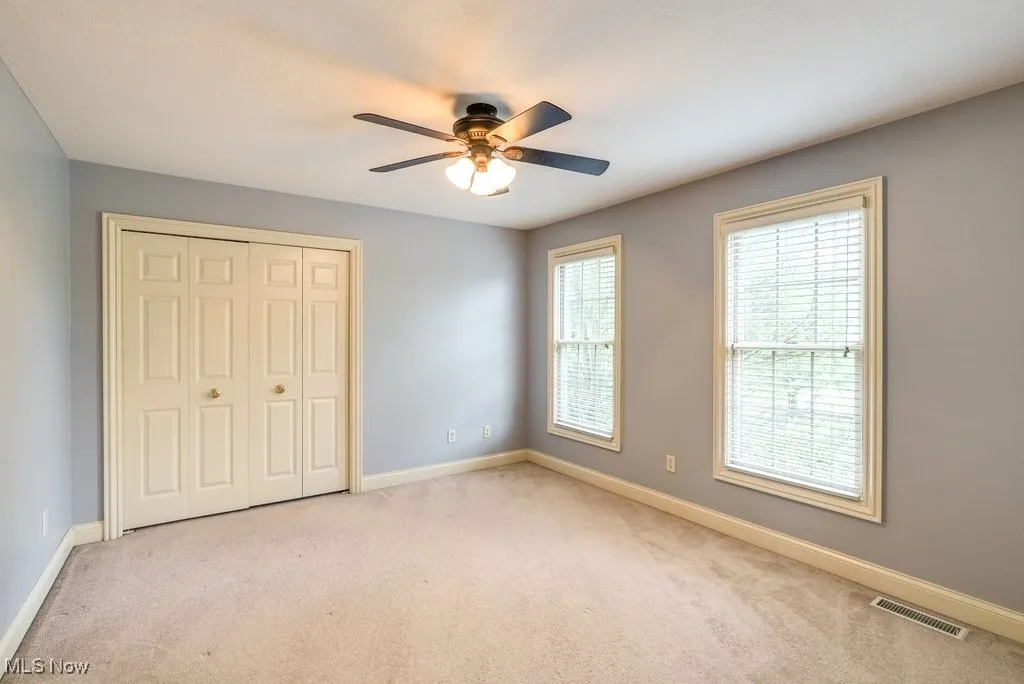 Unfurnished bedroom with light carpet, a closet, and ceiling fan
