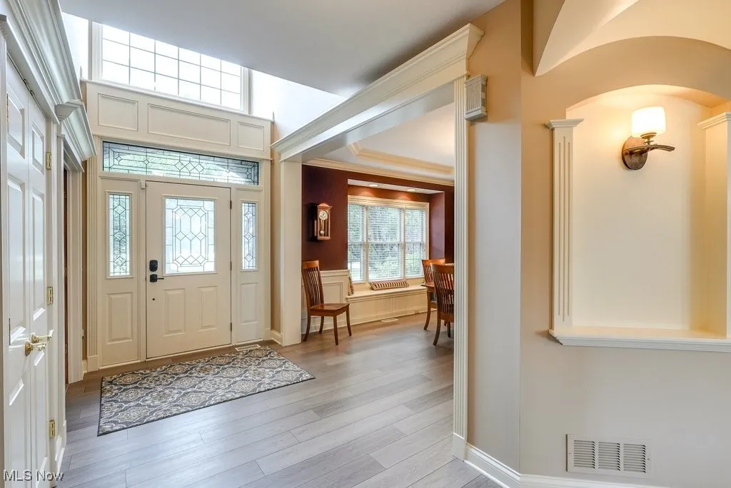 Entryway featuring light wood-type flooring and crown molding