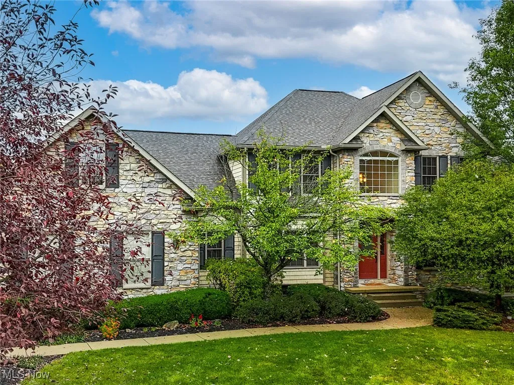 Craftsman-style house featuring stone siding, a front lawn, and roof with shingles