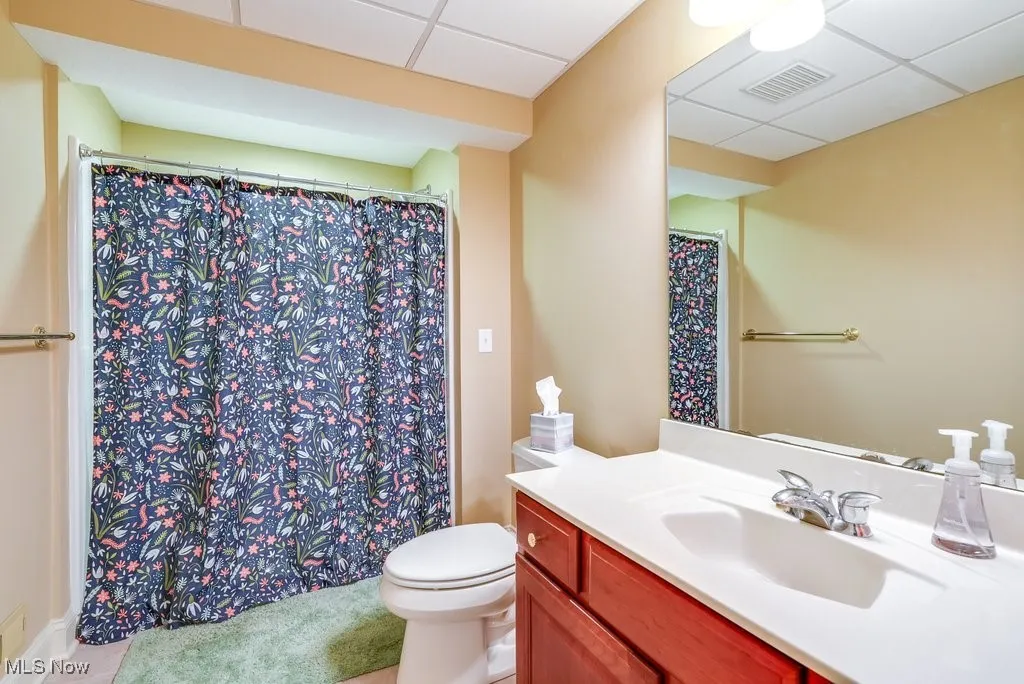 Bathroom featuring tile patterned flooring, a paneled ceiling, vanity, and toilet