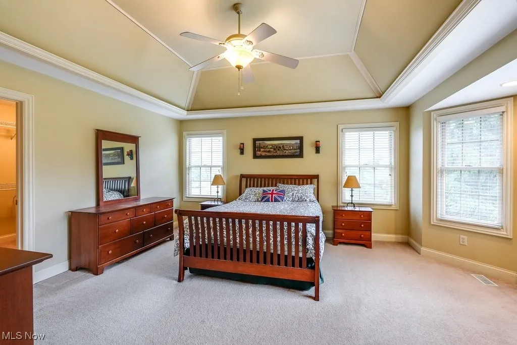 Carpeted bedroom with ornamental molding, lofted ceiling, multiple windows, and ceiling fan