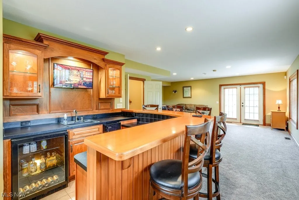 Kitchen with a kitchen breakfast bar, beverage cooler, french doors, sink, and light colored carpet