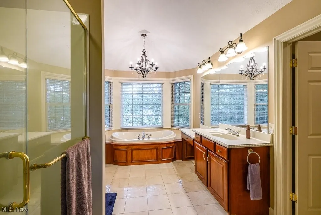 Bathroom with vanity, an inviting chandelier, plus walk in shower, and tile patterned flooring