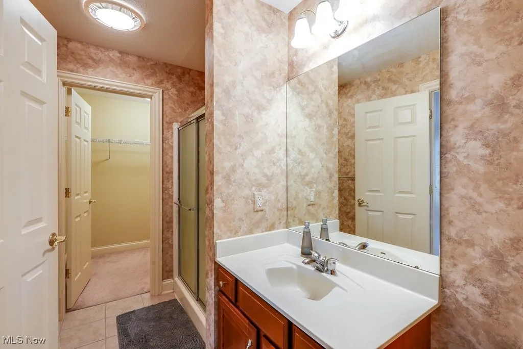 Bathroom featuring tile patterned floors, a shower with door, and vanity