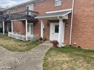View of exterior entry with a balcony and a lawn