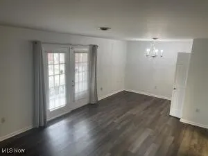 Empty room featuring french doors, a chandelier, and dark hardwood / wood-style flooring
