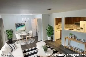 Living room featuring dark wood-type flooring and a notable chandelier