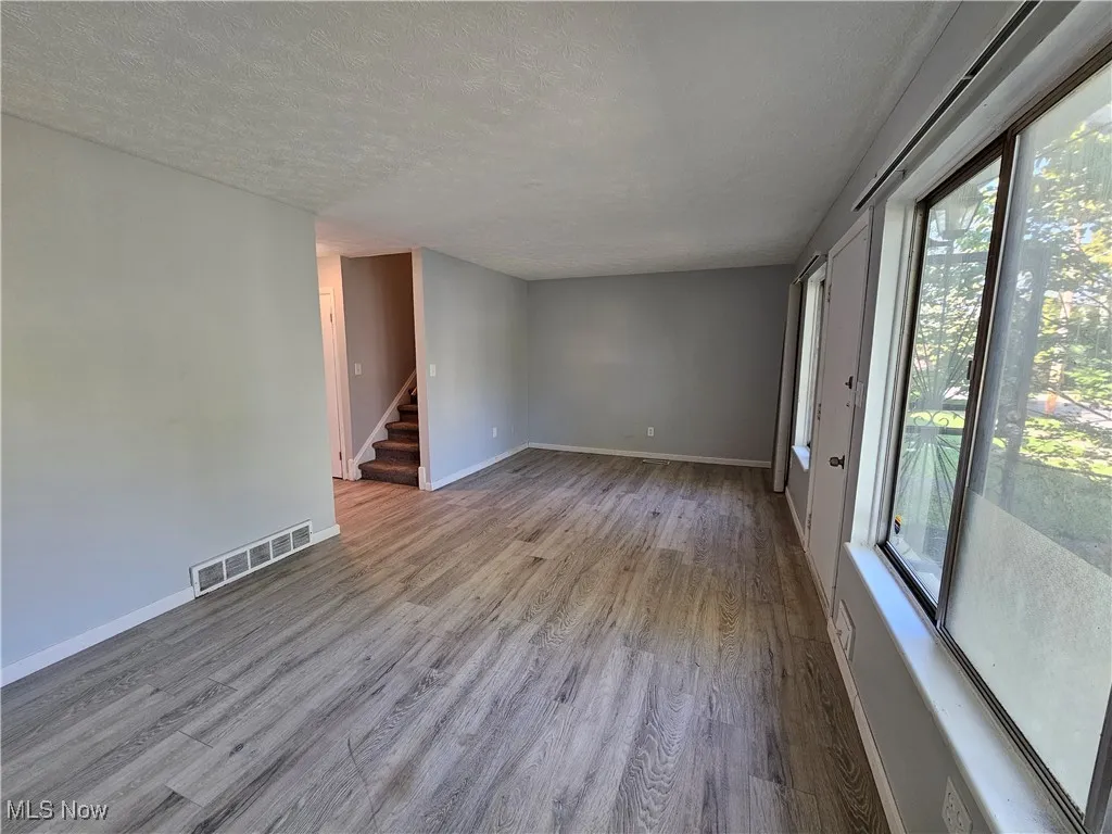 Unfurnished room with a textured ceiling and light wood-type flooring