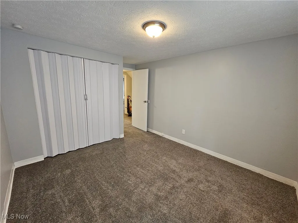 Unfurnished bedroom featuring a textured ceiling and a closet