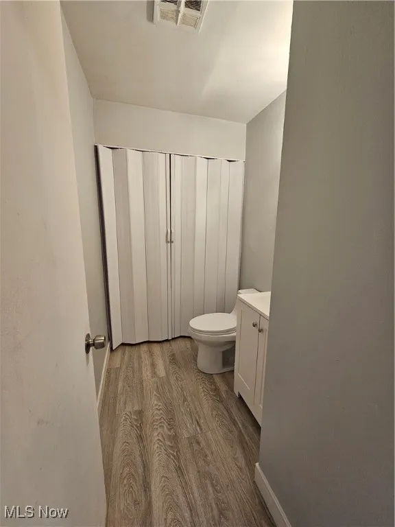 Bathroom with toilet, vanity, and hardwood / wood-style floors