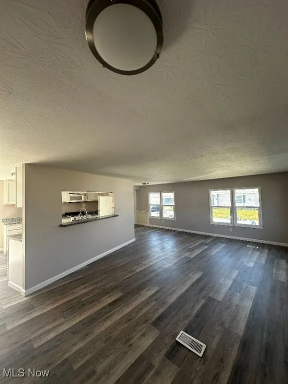 Unfurnished living room with dark hardwood / wood-style flooring and a textured ceiling