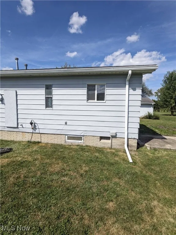 View of side of property with a lawn