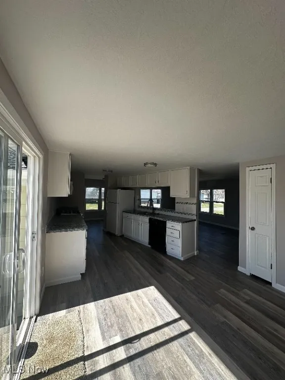 Kitchen with white cabinets, white refrigerator, sink, dark wood-type flooring, and dishwasher