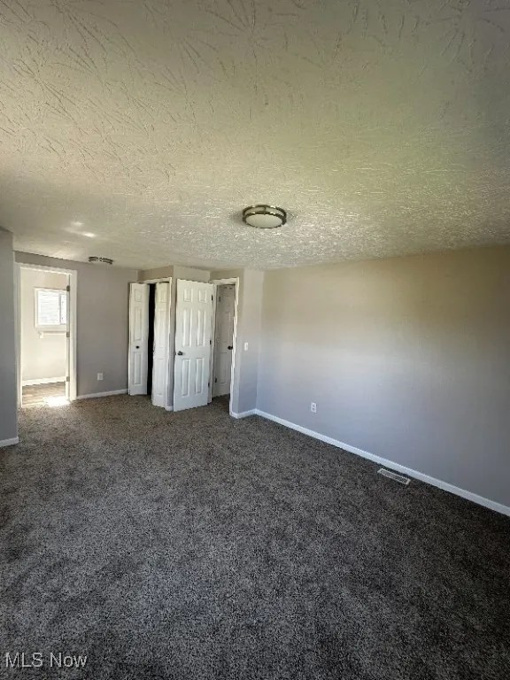 Unfurnished bedroom featuring carpet and a textured ceiling