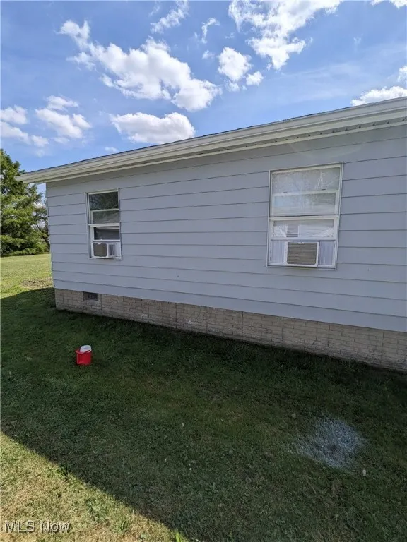View of side of property with cooling unit and a lawn