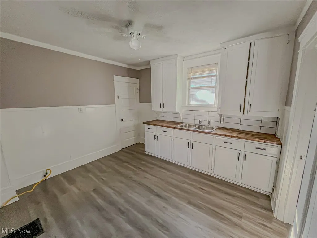 Kitchen with white cabinetry, light hardwood / wood-style floors, wood counters, and ceiling fan