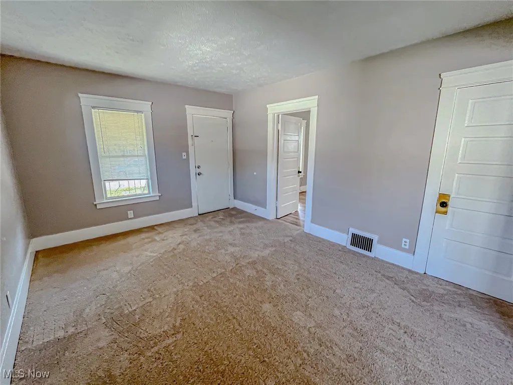 Unfurnished room featuring carpet and a textured ceiling