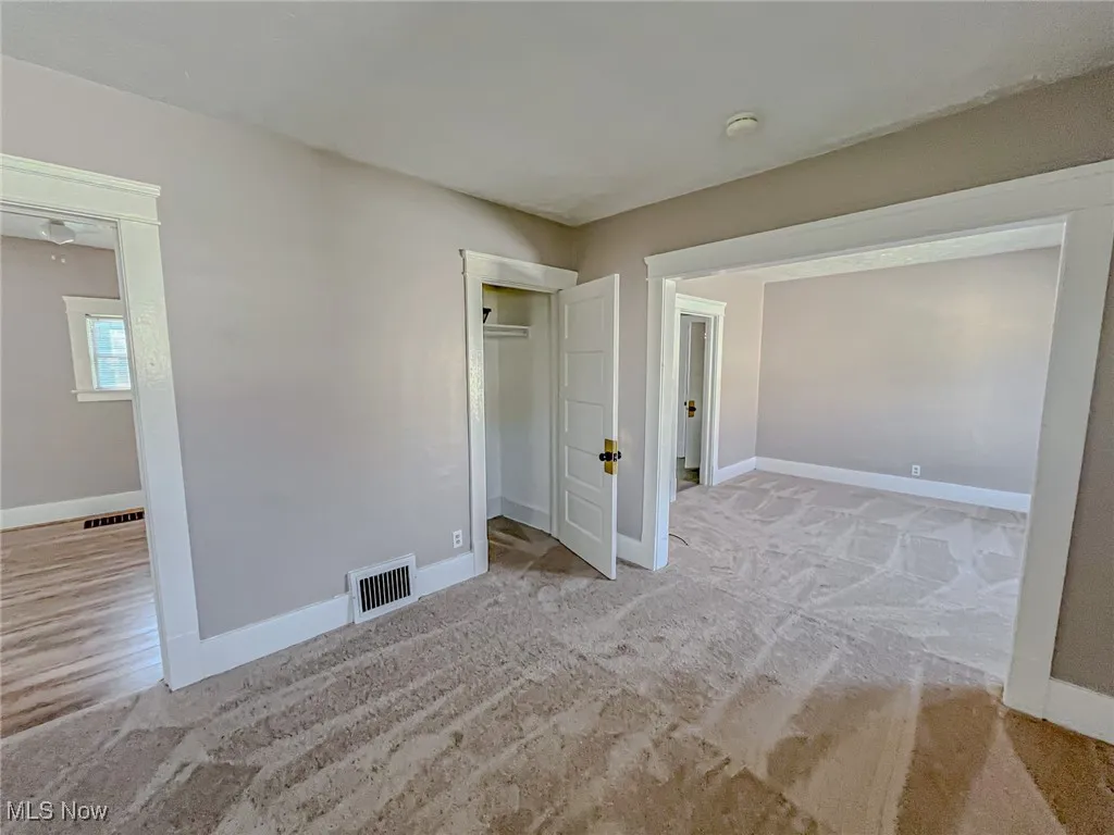 Unfurnished bedroom featuring a closet and light colored carpet