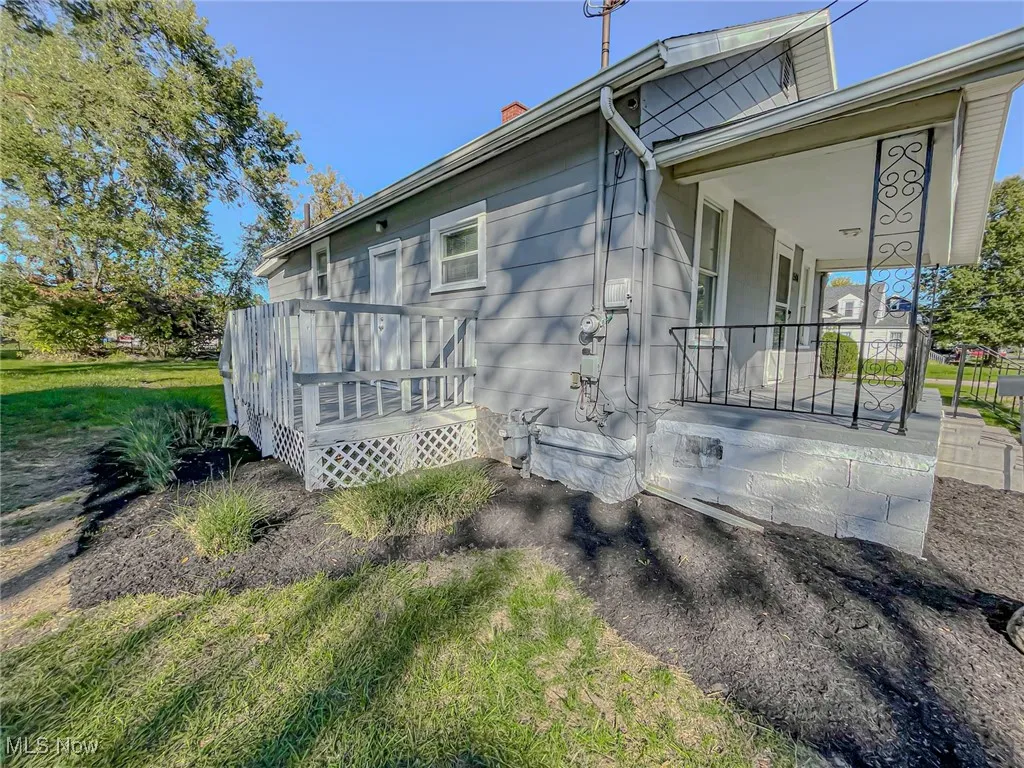 View of home's exterior featuring a wooden deck and a lawn