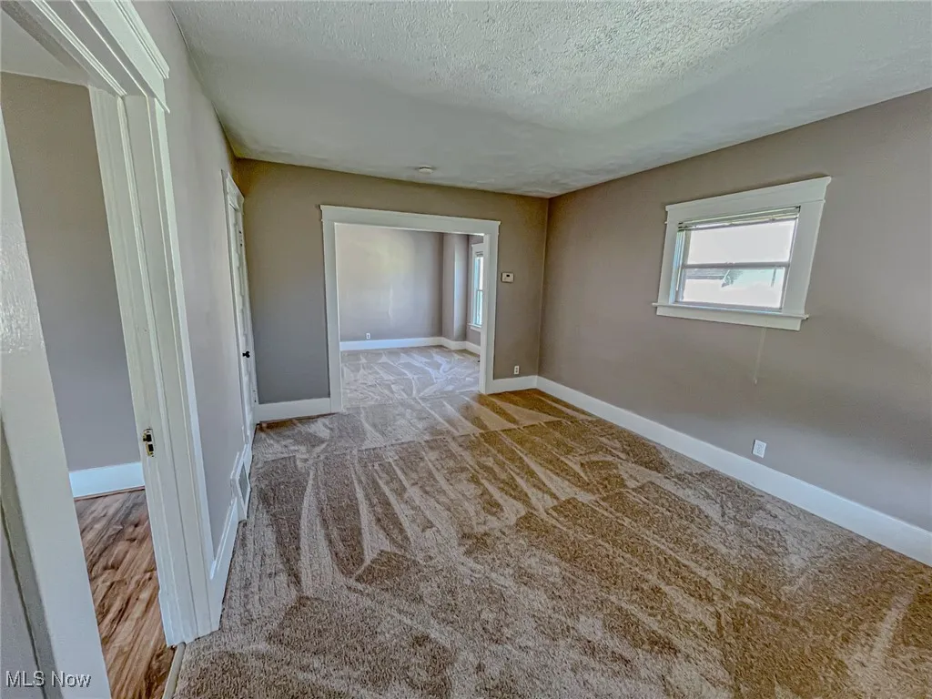 Carpeted empty room featuring a textured ceiling