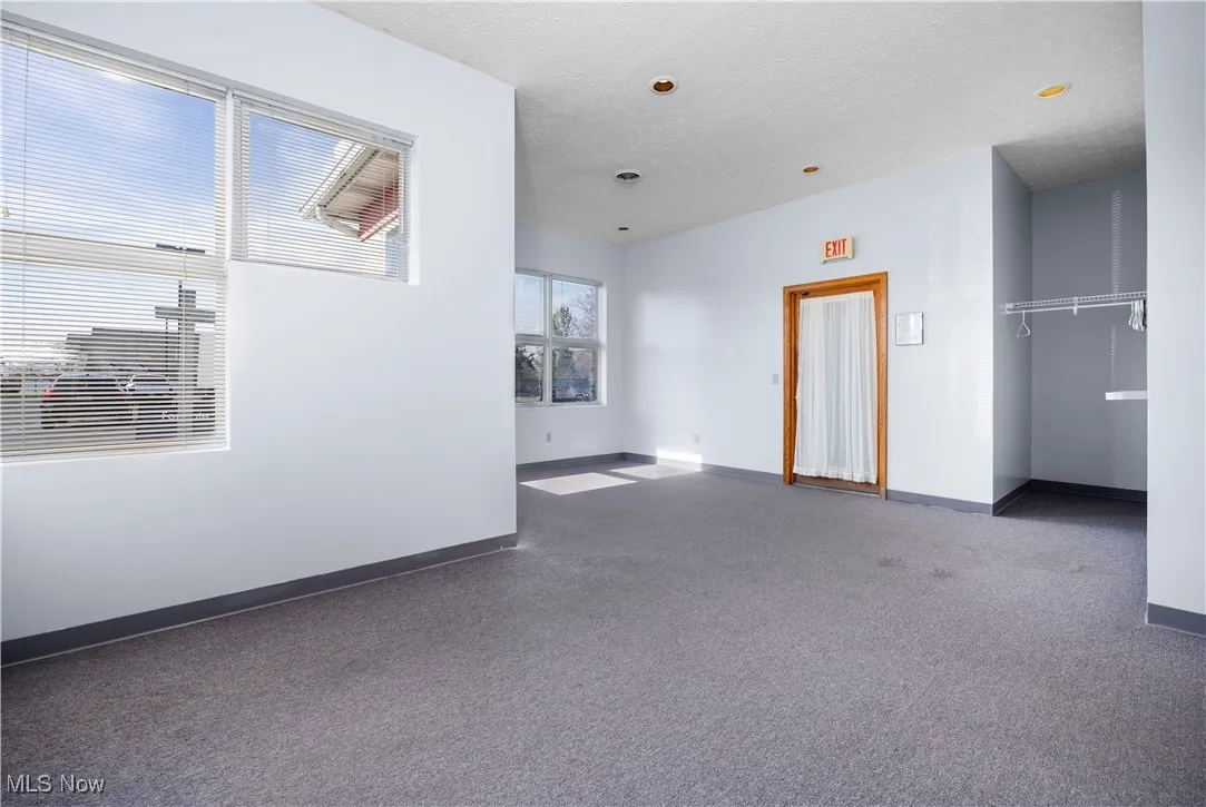 Empty room featuring a textured ceiling and dark carpet