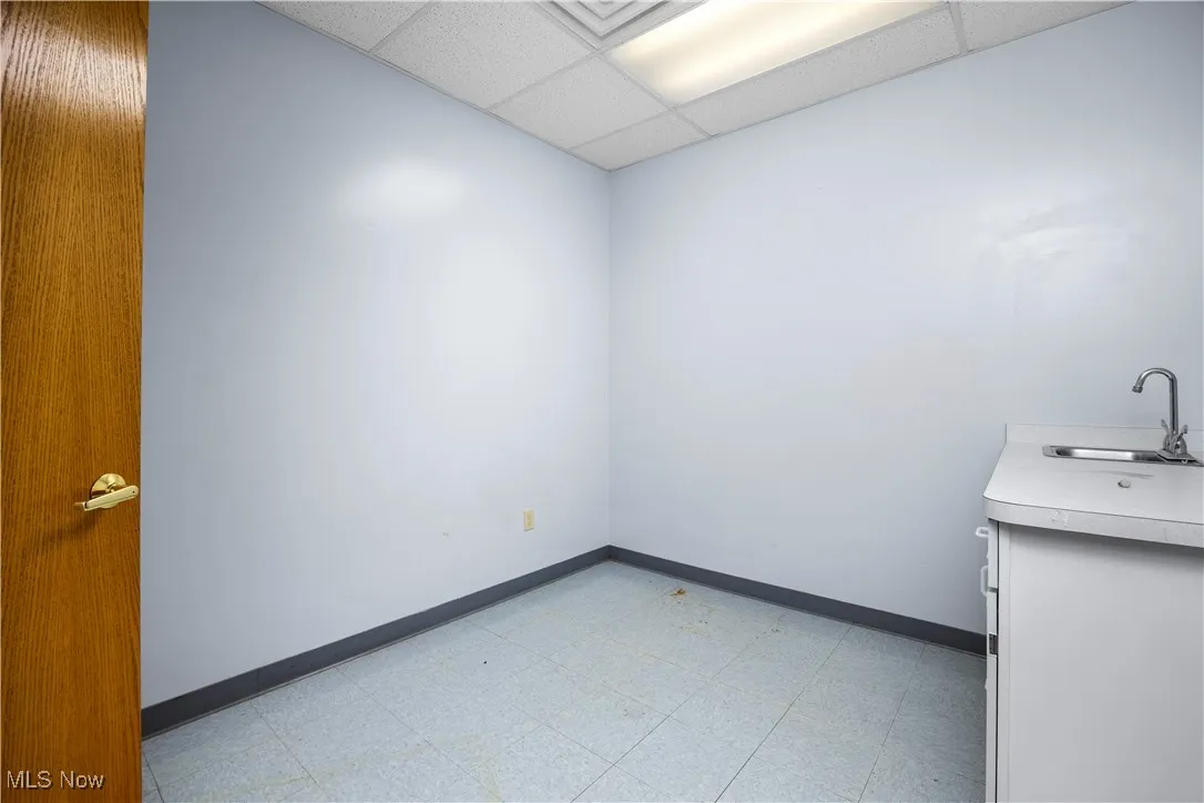 Empty room featuring a paneled ceiling and sink