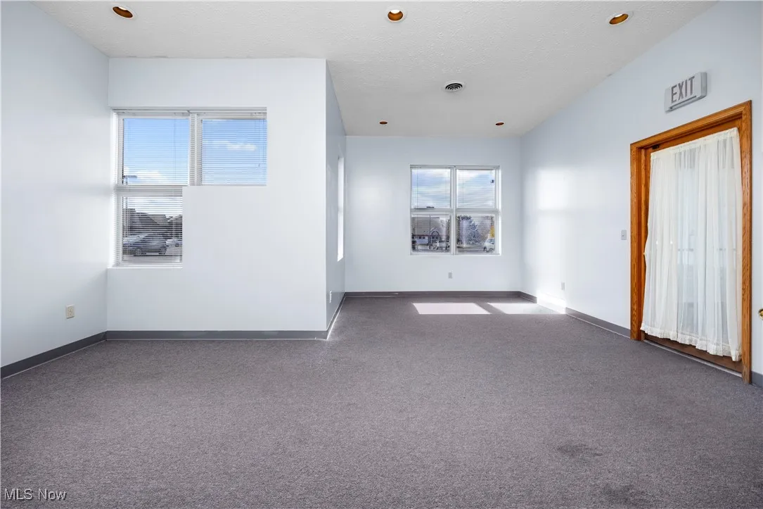 Spare room featuring dark colored carpet and a textured ceiling