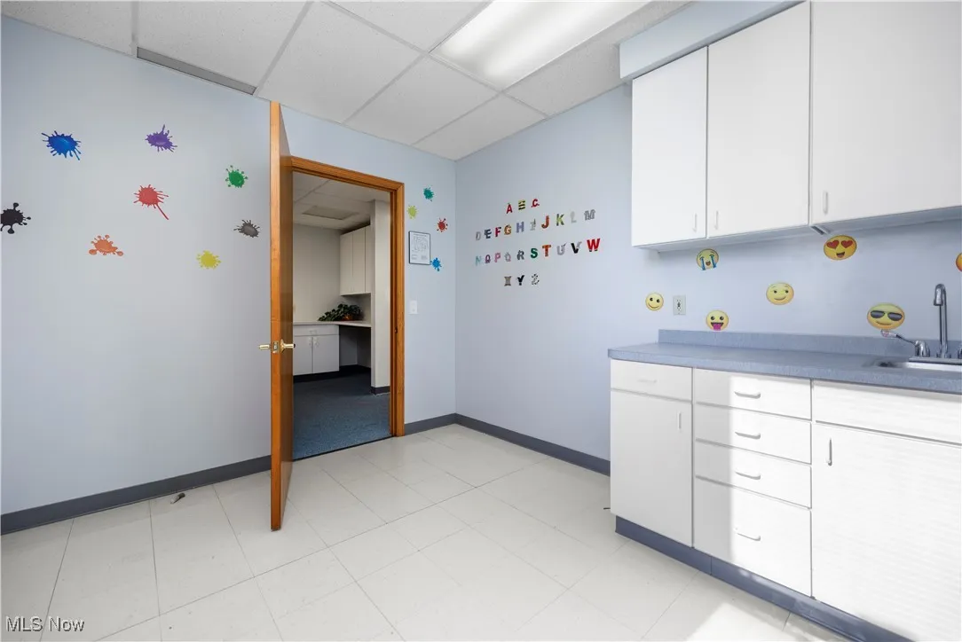 Kitchen with white cabinets, a paneled ceiling, and sink