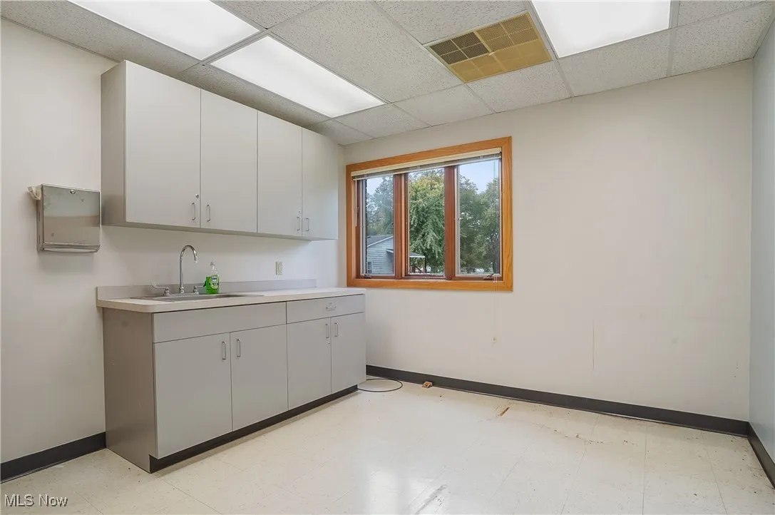 Kitchen with sink, white cabinetry, and a drop ceiling