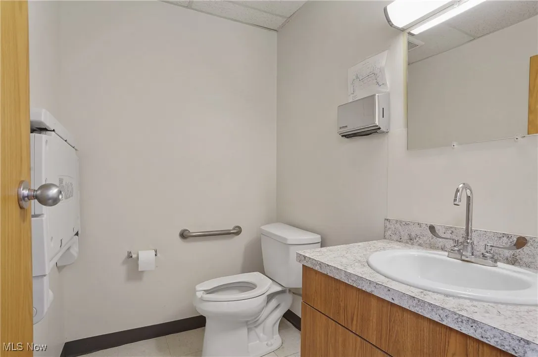 Bathroom with vanity, a paneled ceiling, toilet, and tile patterned floors