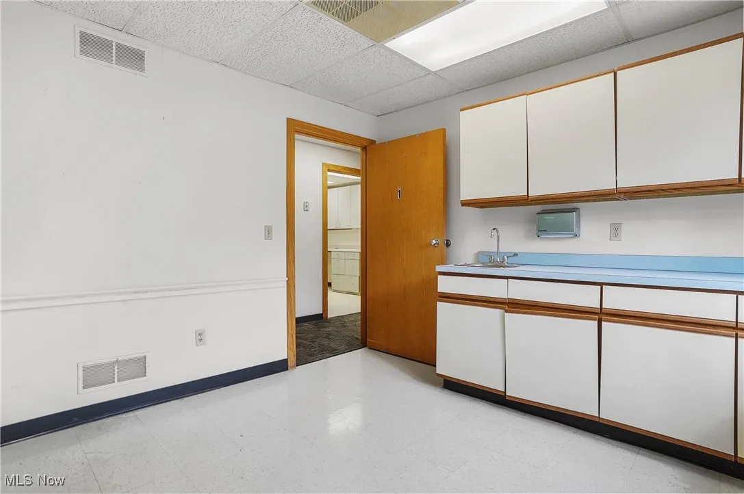 Kitchen featuring white cabinetry, sink, and a paneled ceiling
