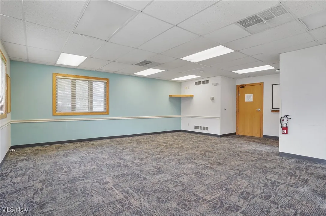 Carpeted empty room featuring a paneled ceiling