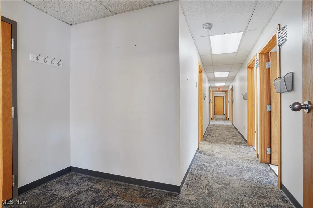 Hall with dark carpet and a paneled ceiling